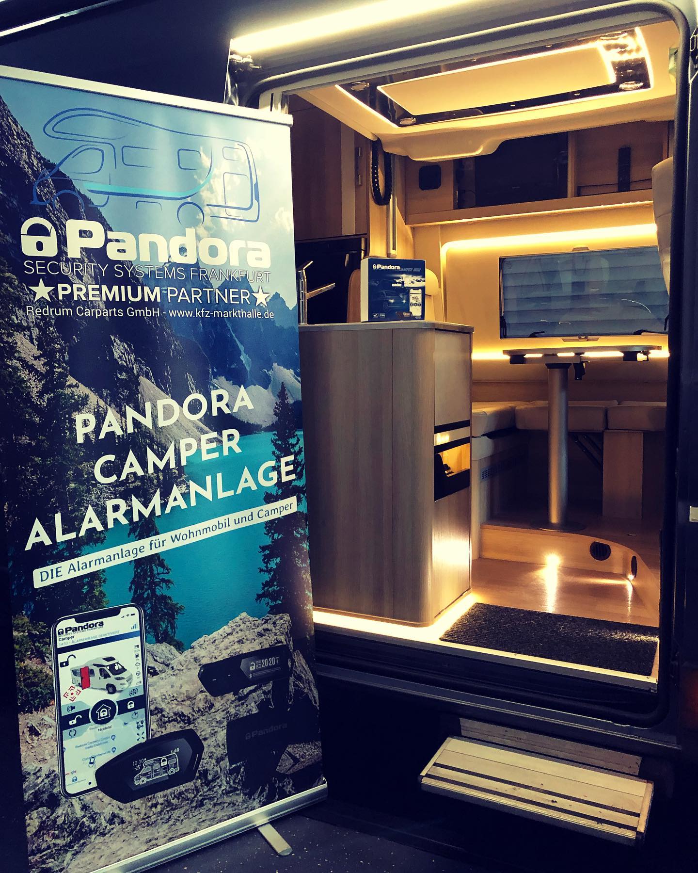 Beleuchteter Einstiegsbereich des Dreamer auf Fiat-Ducato-Basis mit gut sichtbarem Pandora Camper Banner