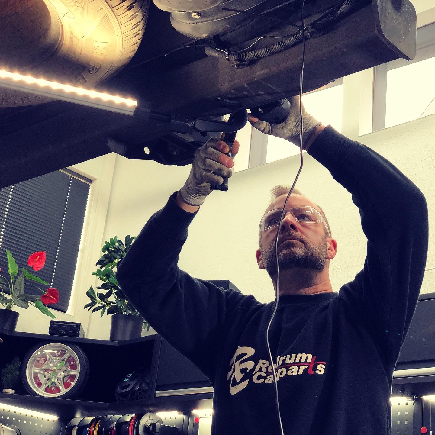 Nahaufnahme von Marco Nolte mit Werkzeug bei der Installation unter dem Fahrzeug