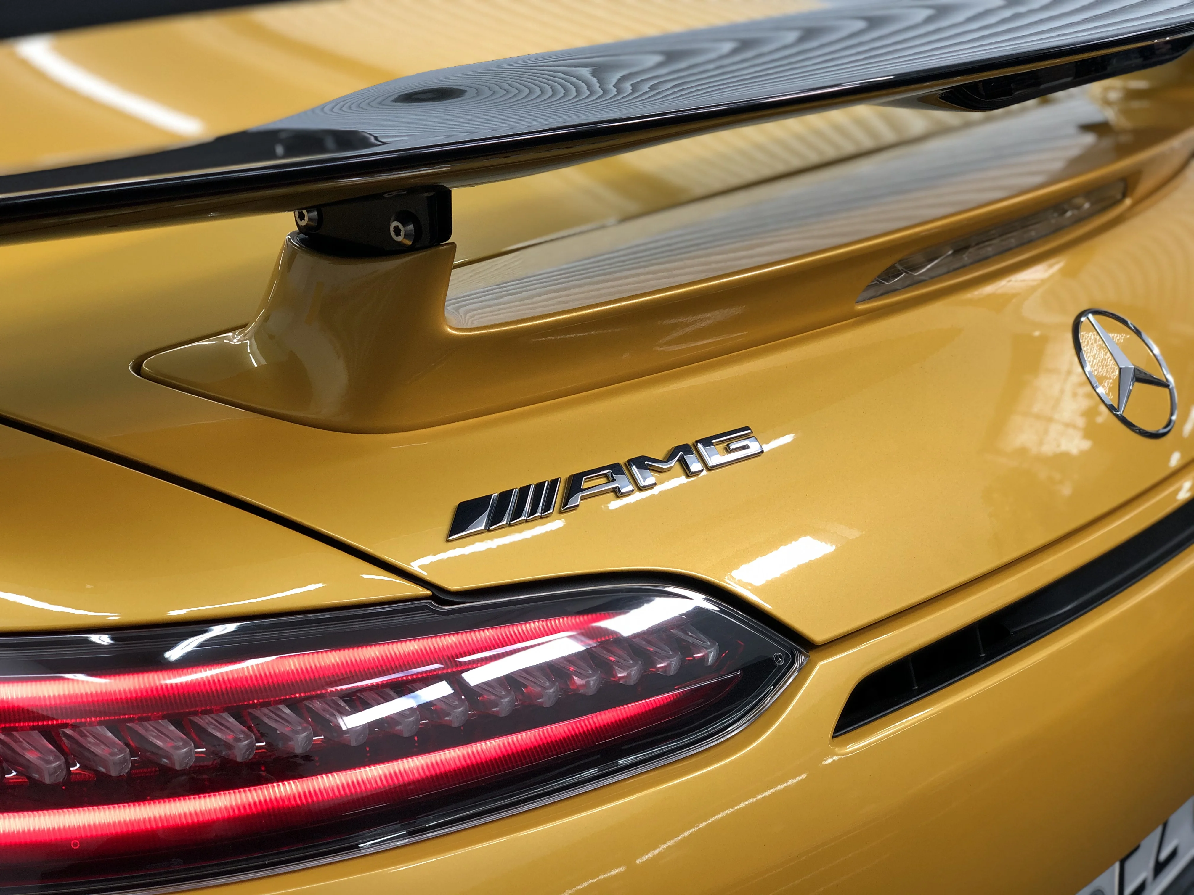 Heckdetail eines gelben Mercedes-AMG mit Spoiler und Rückleuchte