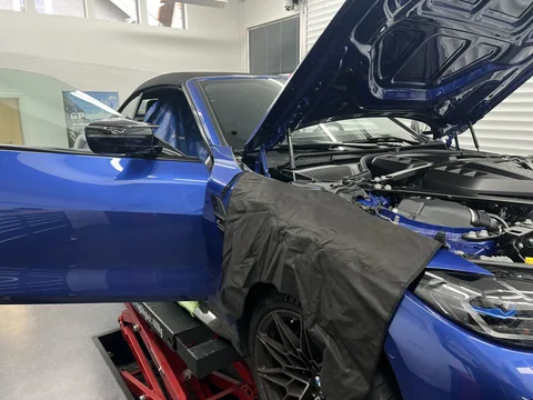 BMW Cabrio mit geöffneter Motorhaube und Schutzmatte am Kotflügel