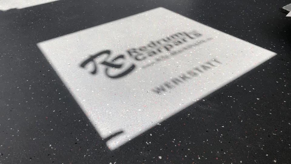 Redrum-Carparts-Logo im Sonnenlicht auf dem Werkstattboden