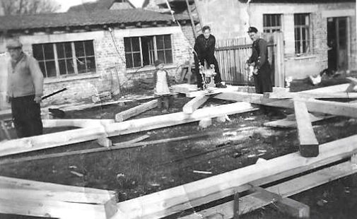 Aufnahme um 1952 mit Holzbalken im Hof und dem Gebäude des heutigen Büros im Hintergrund.